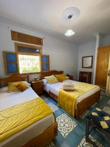 1 dormitorio con 2 camas y ventana en Hôtel Al Kalaa, en Chefchaouen