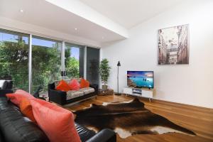 un salon avec un canapé en cuir noir et une télévision dans l'établissement Coral Villa, à Maleny