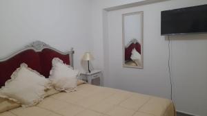 - une chambre avec un lit doté d'oreillers blancs et une télévision dans l'établissement Tiempo, à Mendoza