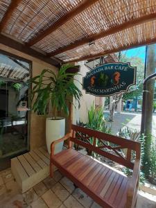 un banco sentado frente a un restaurante con un cartel en Pousada Bar Café Algas Marinhas, en Praia do Forte