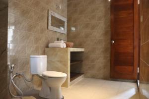 baño con aseo y puerta de madera en Regama Ubud villa en Ubud