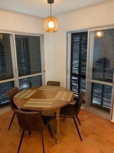 uma sala de jantar com uma mesa e cadeiras de madeira e janelas em Villa Valentina em Carvoeiro