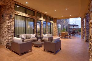 a patio with chairs and tables and a stone wall at Courtyard by Marriott Phoenix Mesa Gateway Airport in Mesa