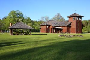 a large red brick building with animals laying in the grass at Recreation Center Brūveri in Sigulda
