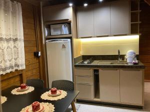 uma pequena cozinha com duas mesas e um frigorífico em Pousada Chalé Flor de Hibisco 1 em Penha