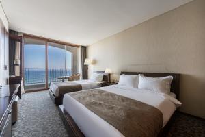 una camera d'albergo con due letti e una grande finestra di Hotel Maremons a Sokcho