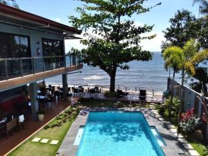 a house with a swimming pool next to the ocean at Baki Divers and Beach Resort in Dauin