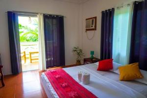 a bedroom with a large bed and a large window at Baki Divers and Beach Resort in Dauin