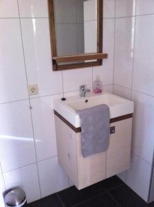 La salle de bains est pourvue d'un lavabo, d'un miroir et d'une baignoire. dans l'établissement Vakantiewoning Zonnige Blik, à Domburg