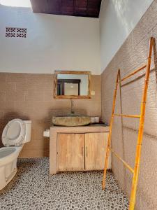 a bathroom with a sink and a toilet and a mirror at Lemon Guest House in Canggu