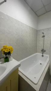 uma casa de banho com uma banheira, um lavatório e flores amarelas em Gold hotel, Saigon em Cidade de Ho Chi Minh