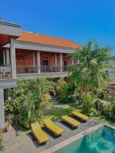 un complejo con tumbonas amarillas y piscina en Lemon Guest House, en Canggu