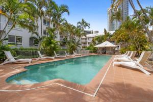 a swimming pool with lounge chairs and palm trees at Bay Lodge - Private Apartments in Gold Coast