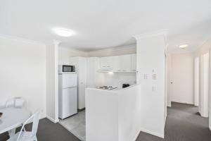 eine weiße Küche mit einer weißen Theke und einem Tisch in der Unterkunft Bay Lodge - Private Apartments in Gold Coast
