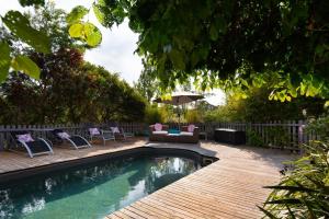 a backyard with a swimming pool and chairs and an umbrella at Gables Bend On High in Daylesford