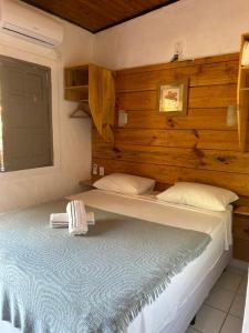 a bedroom with a large bed with a wooden wall at Pousada Bar Café Algas Marinhas in Praia do Forte