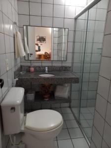 a bathroom with a toilet and a sink and a mirror at Apartamento Porto das Dunas in Aquiraz
