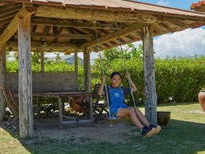 a young girl sitting on a swing under a pavilion at Pension Snadun in Ginoza