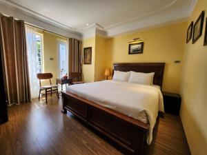 sypialnia z dużym łóżkiem i krzesłem w obiekcie Classic Street Hotel w mieście Hanoi