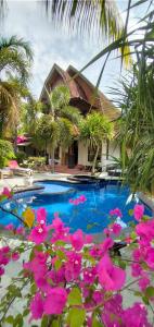 a swimming pool with pink flowers in front of a house at Gili Moonlight Retreat in Gili Air