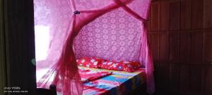 a canopy bed with red pillows in a room at Farmer home stay & trekking in Banlung
