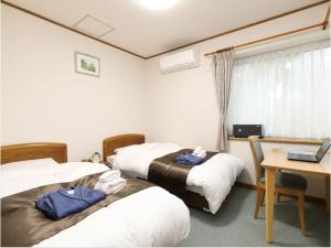 Habitación de hotel con 3 camas y escritorio con ordenador portátil. en Pension Hinode, en Hachimantai
