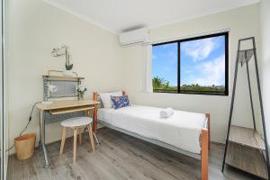 a bedroom with a bed and a desk and a window at Campsie Adorable 3Br Apt with Wifi & Parking in Sydney