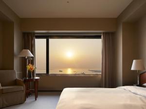 een slaapkamer met een groot raam met uitzicht op de oceaan bij Grand Prince Hotel Osaka Bay in Osaka