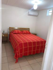 um quarto com uma cama vermelha e um cobertor vermelho em Case rouge em Les Abymes