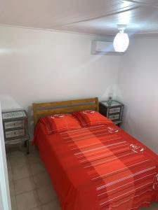 um quarto com uma cama com um edredão vermelho em Case rouge em Les Abymes