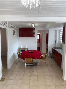 uma sala de jantar com uma mesa vermelha e cadeiras em Case rouge em Les Abymes