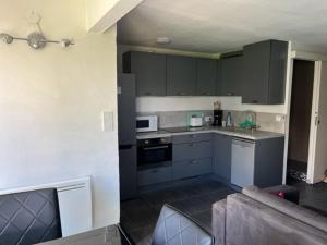 a kitchen with gray cabinets and a couch in a room at Appartement Cap d'Agde, 3 pièces, 4 personnes - FR-1-749-9 in Cap d'Agde