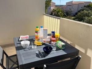 einen Tisch mit Speisen und Getränken auf dem Balkon in der Unterkunft Appartement Cap d'Agde, 3 pièces, 4 personnes - FR-1-749-11 in Cap d'Agde