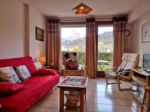 un soggiorno con divano rosso e una grande finestra di Appartement cosy avec terrasse - 6 pers, proche pistes et commerces, parking inclus - FR-1-595-81 a Notre-Dame-de-Bellecombe