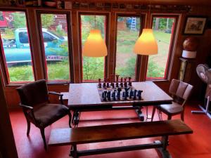 un tablero de ajedrez sobre una mesa en una habitación con ventanas en Chalet en bois rond Mauricie en Saint-Alexis-des-Monts