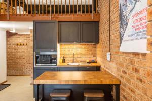 a kitchen with black cabinets and a brick wall at Alpine Gables 11 2 Clyde Street in Jindabyne