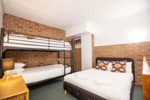 two bunk beds in a room with a brick wall at Alpine Gables 11 2 Clyde Street in Jindabyne