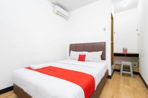 um quarto com uma grande cama branca e um cobertor vermelho em RedDoorz @ Tanjung Sari Surabaya em Tandjung-lor