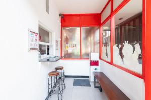 a restaurant with a red window and stools in front at RedDoorz @ Tanjung Sari Surabaya in Tandjung-lor