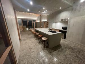 a kitchen with a sink and a counter with stools at Amami 与庵 in Amami