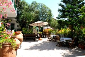 un patio con mesas, sillas y una sombrilla en Topakas House, en Kambos