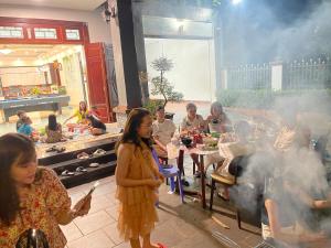 木州的住宿－Chelsea Villa Moc Chau Venuestay，一群人站在厨房周围,一边吃食物