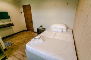 um pequeno quarto com uma cama e uma televisão de ecrã plano em Midway Stay Apartments Dumaguete em Dumaguete