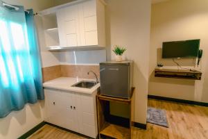 uma pequena cozinha com um lavatório e uma televisão em Midway Stay Apartments Dumaguete em Dumaguete