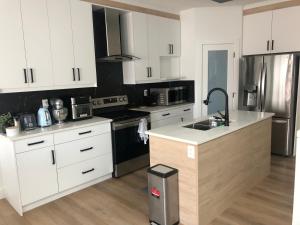 cocina con armarios blancos y encimera en Room in a New Guest House, en Fort Saskatchewan