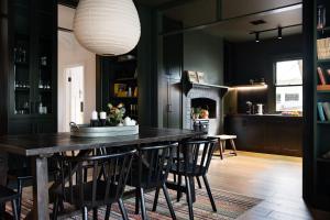 un comedor con una gran mesa de madera y paredes negras en Hambleden, en Daylesford