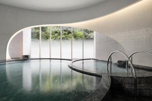 - une piscine dans un bâtiment avec une grande fenêtre dans l'établissement The Westin Miyako Kyoto, à Kyoto