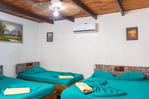 2 Betten in einem Zimmer mit blauer Bettwäsche in der Unterkunft Hotel El Baquiano in Tamarindo