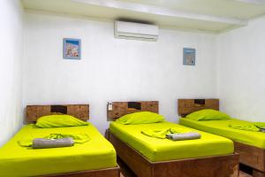 two beds in a room with yellow sheets and pillows at Hotel El Baquiano in Tamarindo