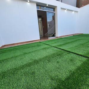 a room with a green field of grass next to a building at La casa de Teo in Ica